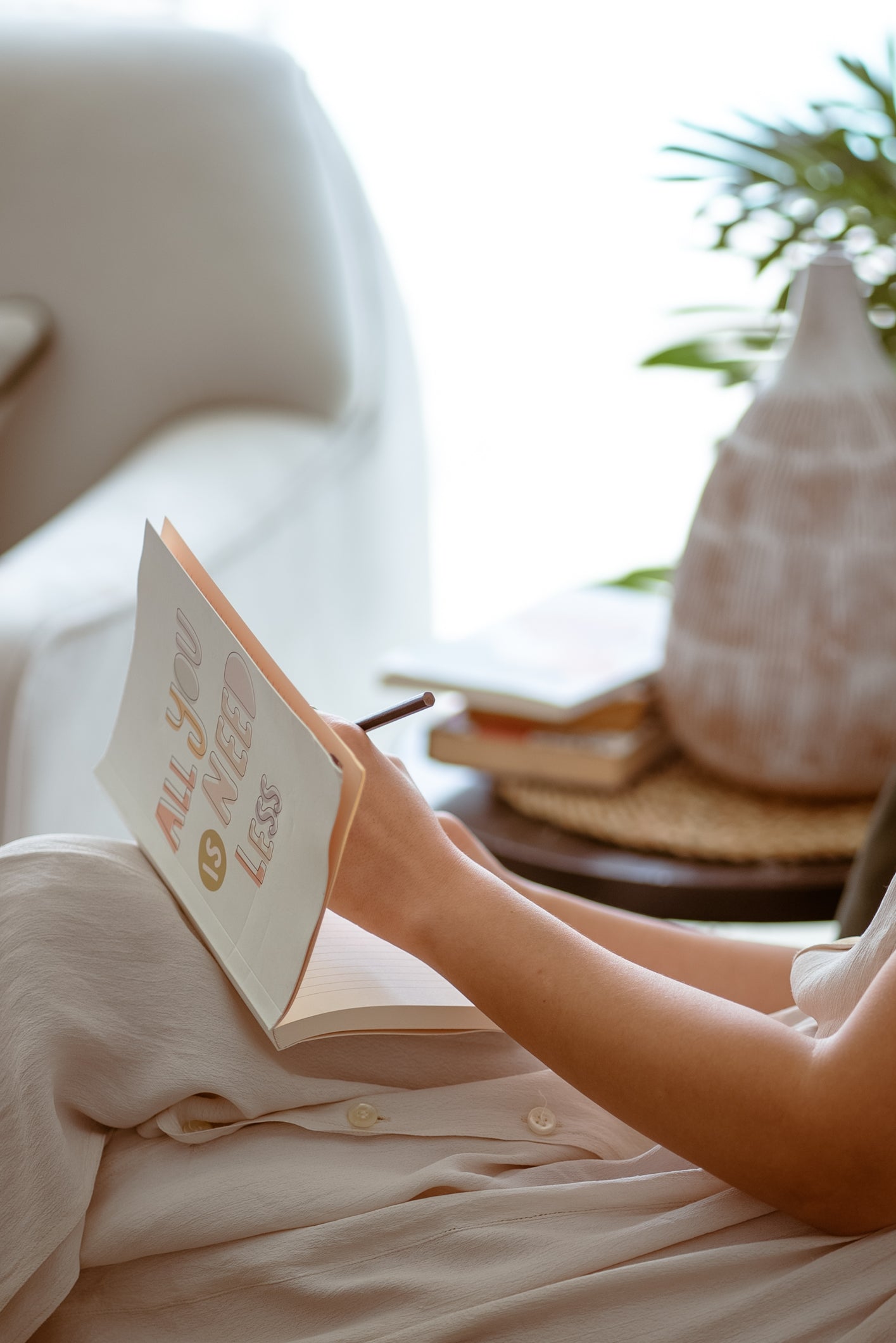 Woman Sitting on a Couch and Writing in a Notebook