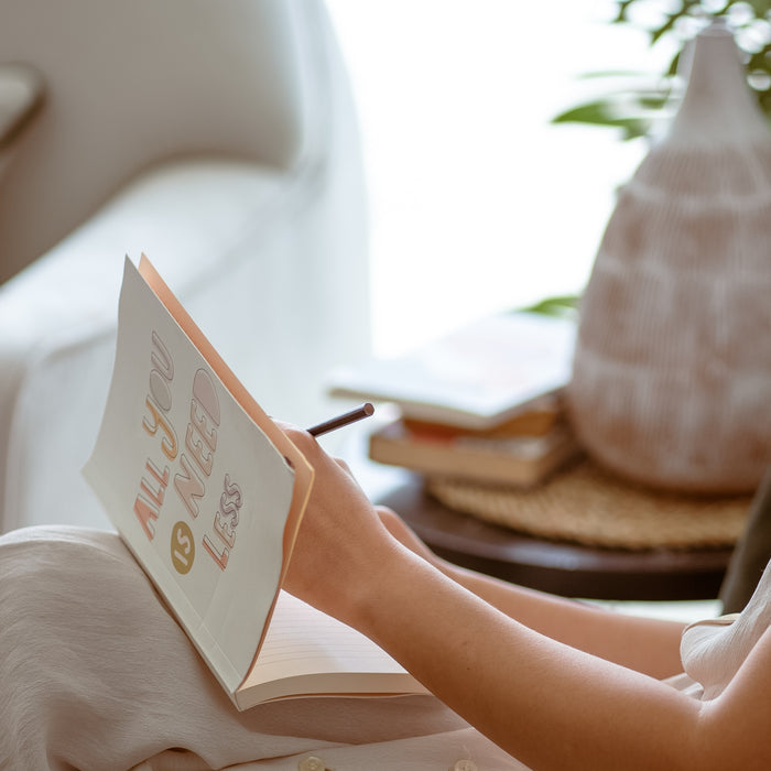 Woman Sitting on a Couch and Writing in a Notebook